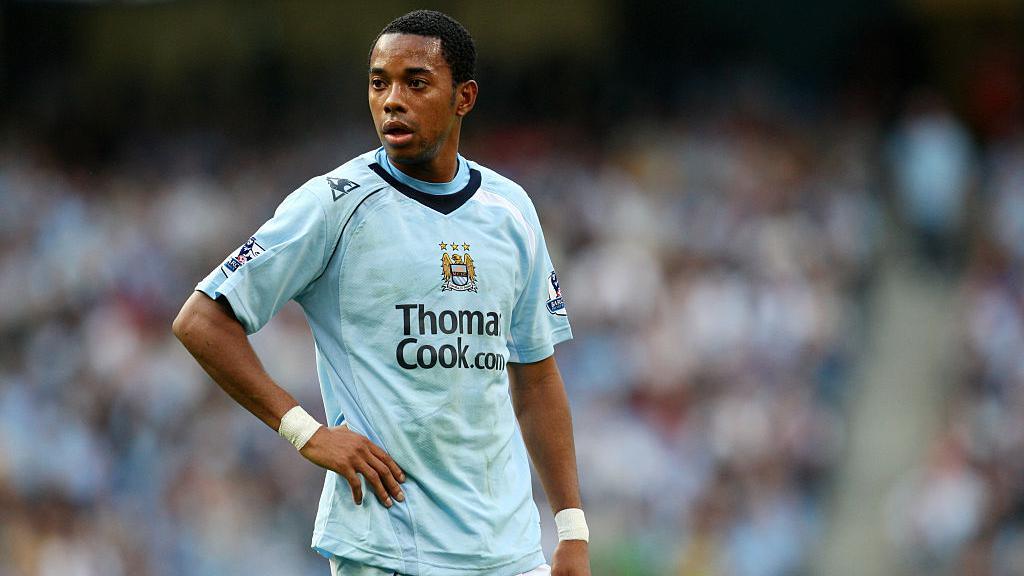 Mark Hughes ungkap cerita lucu: Robinho sempat mengira bergabung Manchester United, ternyata Manchester City. Kisah transfer tak terlupakan.
