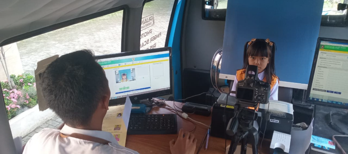 Seorang siswa tampak serius saat difoto di dalam mobil layanan Dukcapil Kota Mataram untuk pembuatan Kartu Identitas Anak (KIA).