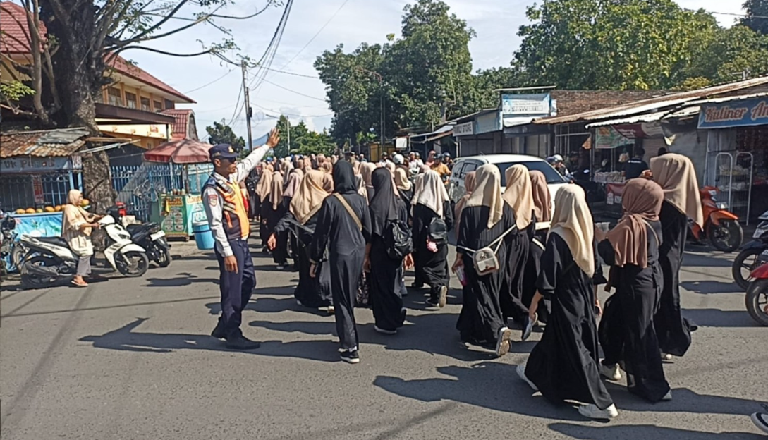 Dengan gestur tangan tegas, petugas Dishub Kota Mataram memberi aba-aba kepada pengendara agar memberi jalan bagi peserta pawai.