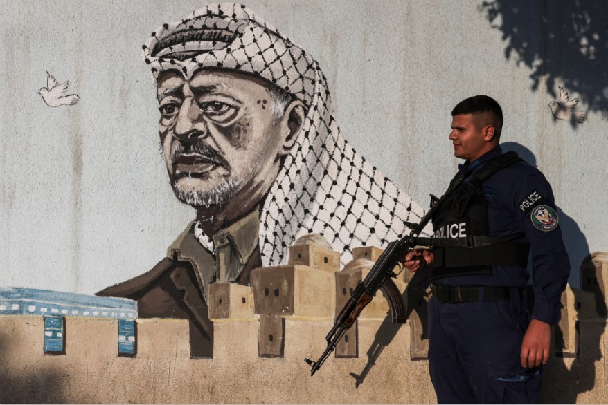 BERJAGA: Polisi Palestina berjaga di luar kantor polisi yang dihiasi mural mendiang pemimpin Palestina Yasser Arafat, di kota Hebron, Tepi Barat, Selasa (11/11).