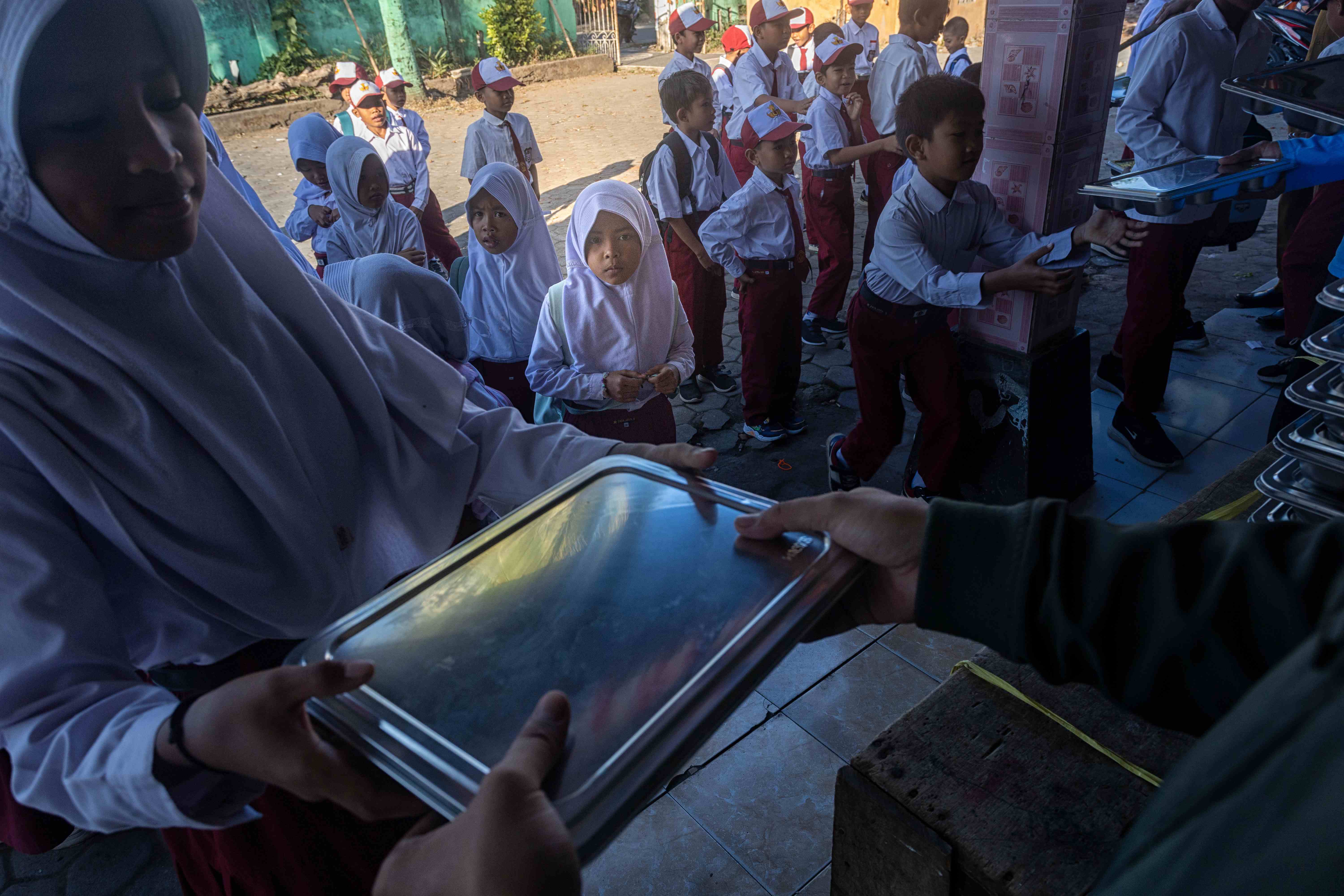 SASARAN MBG: Seorang siswi menerima kotak makan yang berisi santapan MBG, dari petugas SPPG di salah satu SD di NTB, beberapa waktu lalu.