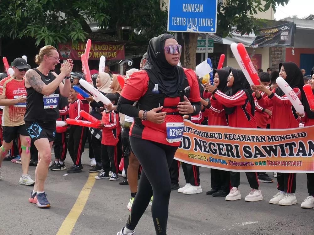 Sejumlah pelari Borobudur Marathon 2025 mendapatkan semangat dari para siswa SD Sawitan, Mungkid, Minggu (16/11/2025). (ROFIK SYARIF/ JAWAPOS RADAR MAGELANG)
