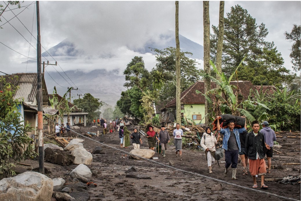 Warga di Desa Supiturang, Lumajang, Jawa Timur berjalan di atas tanah yang tertutup abu vulkanik untuk mengungsi pasca erupsi Gunung Semeru Kamis, (20/11)