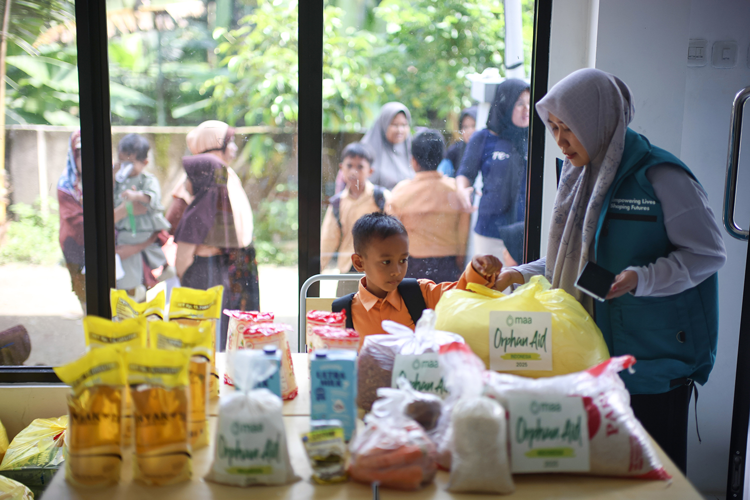 Seorang anak menerima bantuan dari MAA International dan IBM di Desa Giri adia, Lobok Barat, Sabtu 22/11,2025.