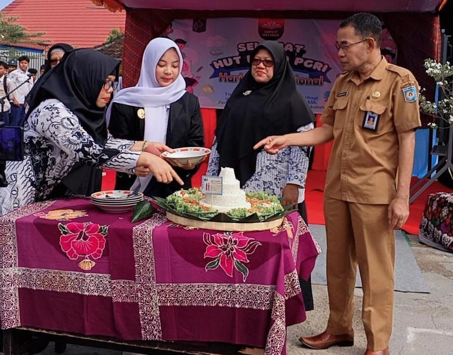 Guru SMPN 17 Mataram memotong tumpeng pada HUT PGRI ke-80 dan HGN di sekolah setempat, Sabtu (25/11). Spentubels gelar berbagi sembako dan pentas seni meriahkan HUT PGRI ke-80 dan HGN 2025.