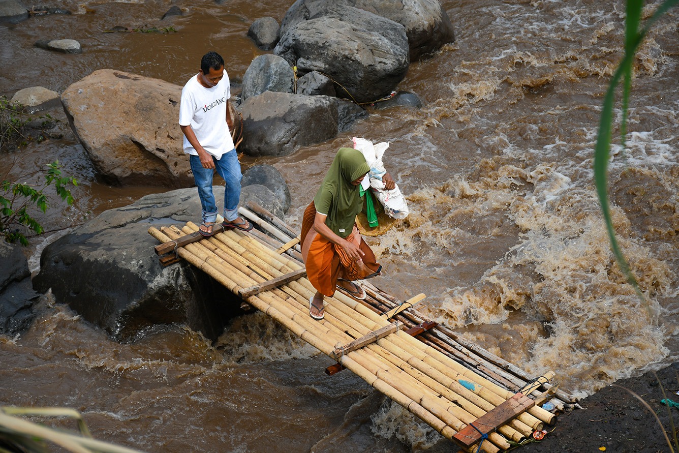 Warga Dusun Beta, Desa Perigi, Kecamatan Suela saat melintas di jembatan sementara yang dibuat dari bambu, beberapa waktu lalu