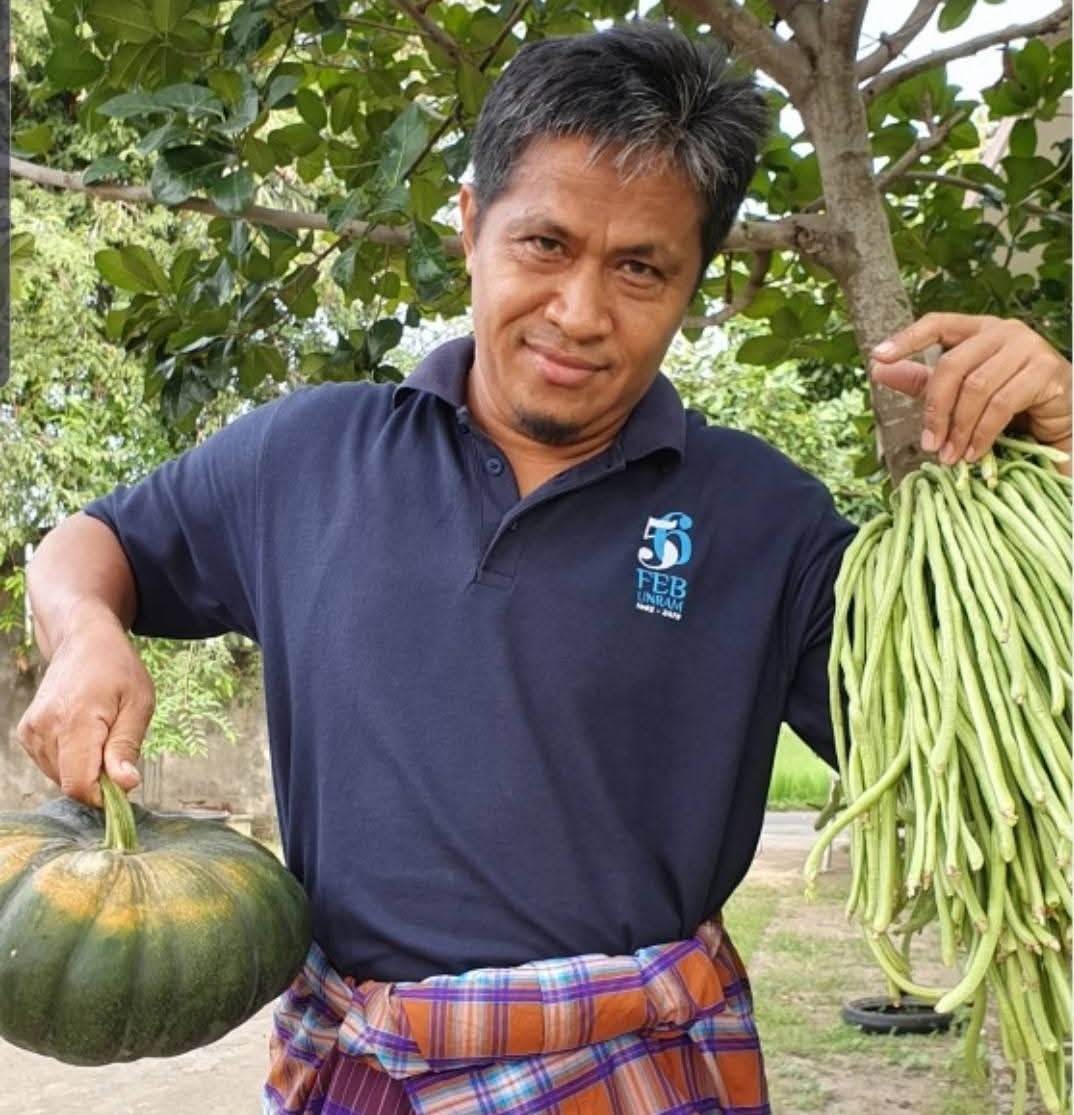 Prof Muhamad Ali memegang labu dan kacang panjang menjadi simbol kepemimpinan yang membumi. Akademisi Unram yang membumi dan dekat dengan petani.