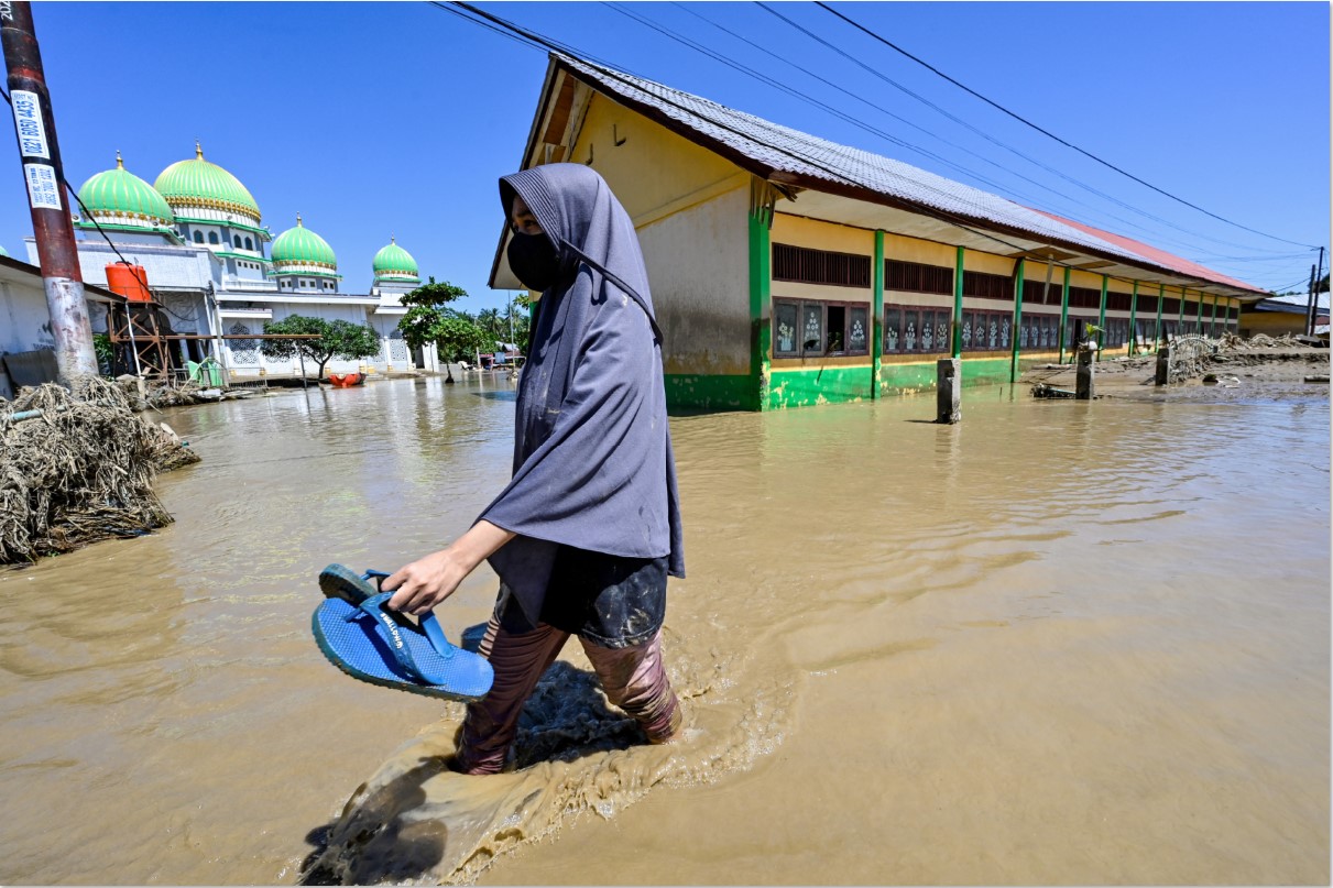Seorang korban banjir saat melalui permukimannya yang terendam banjir, beberapa hari lalu.