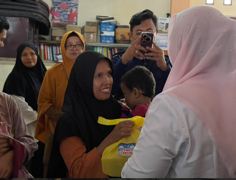 Seorang ibu dan balitanya menerima bingkisan paket makanan bergizi untuk mencegah stunting