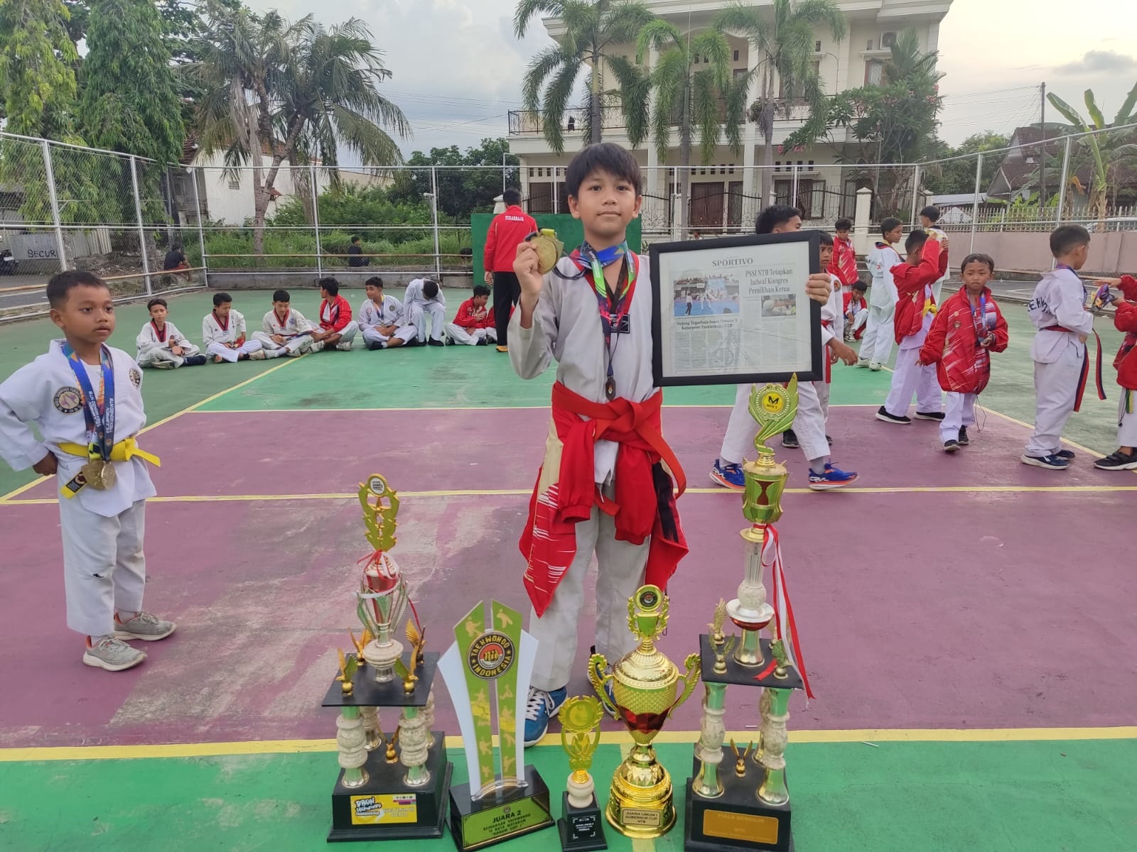 PRESTASI: Salah seorang atlet Dojang Tegar Baja bersama sejumlah piala dan piagam penghargaan.