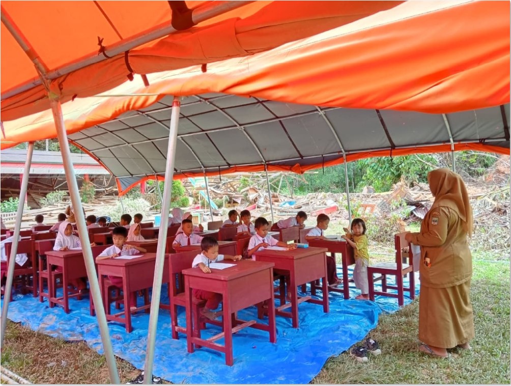 TAK MENYERAH: Para murid SDN 05 Batang Anai, Padang Pariaman, tekun menjalani ujian di bawah tenda BNPB di halaman sekolah pada Senin (8/12). Ujian berlangsung sampai besok (11/12).