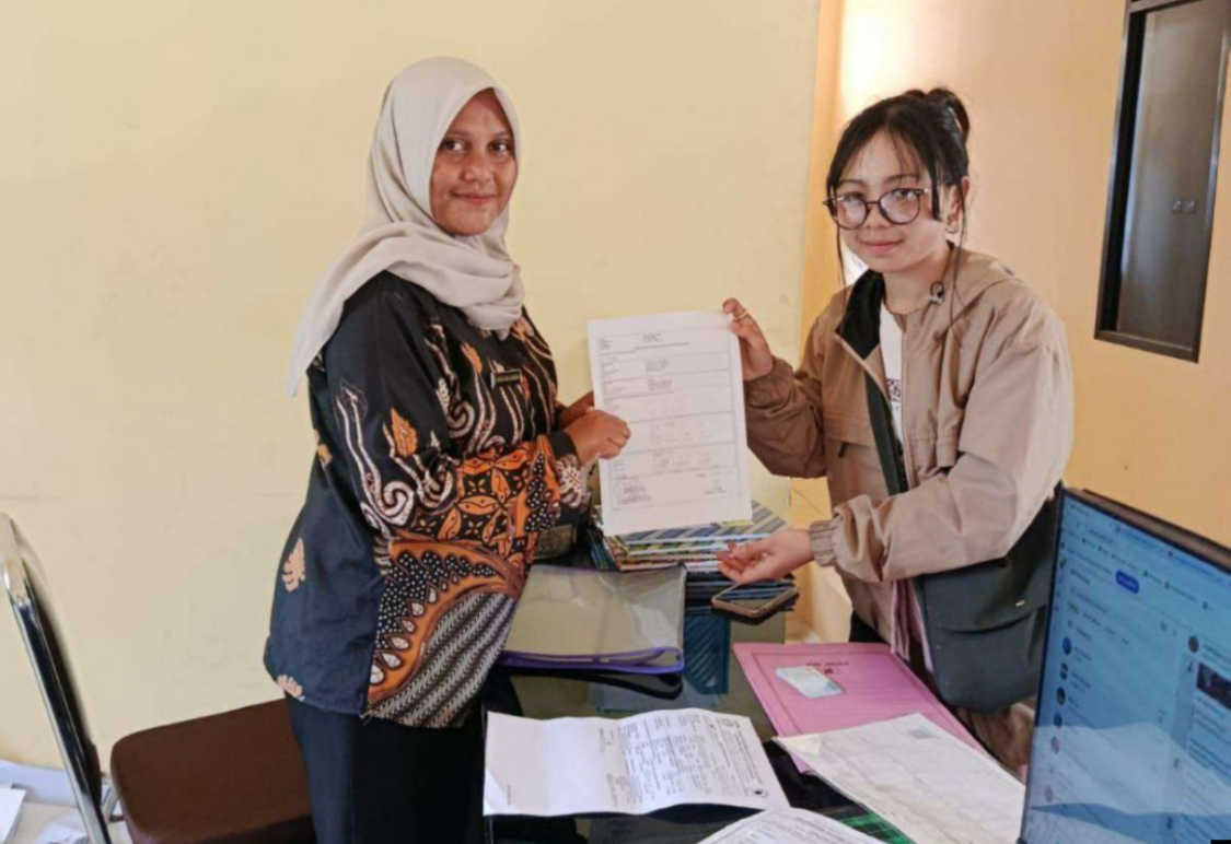 Petugas kelurahan menyerahkan berkas adminduk yang sudah selesai kepada pemohon.