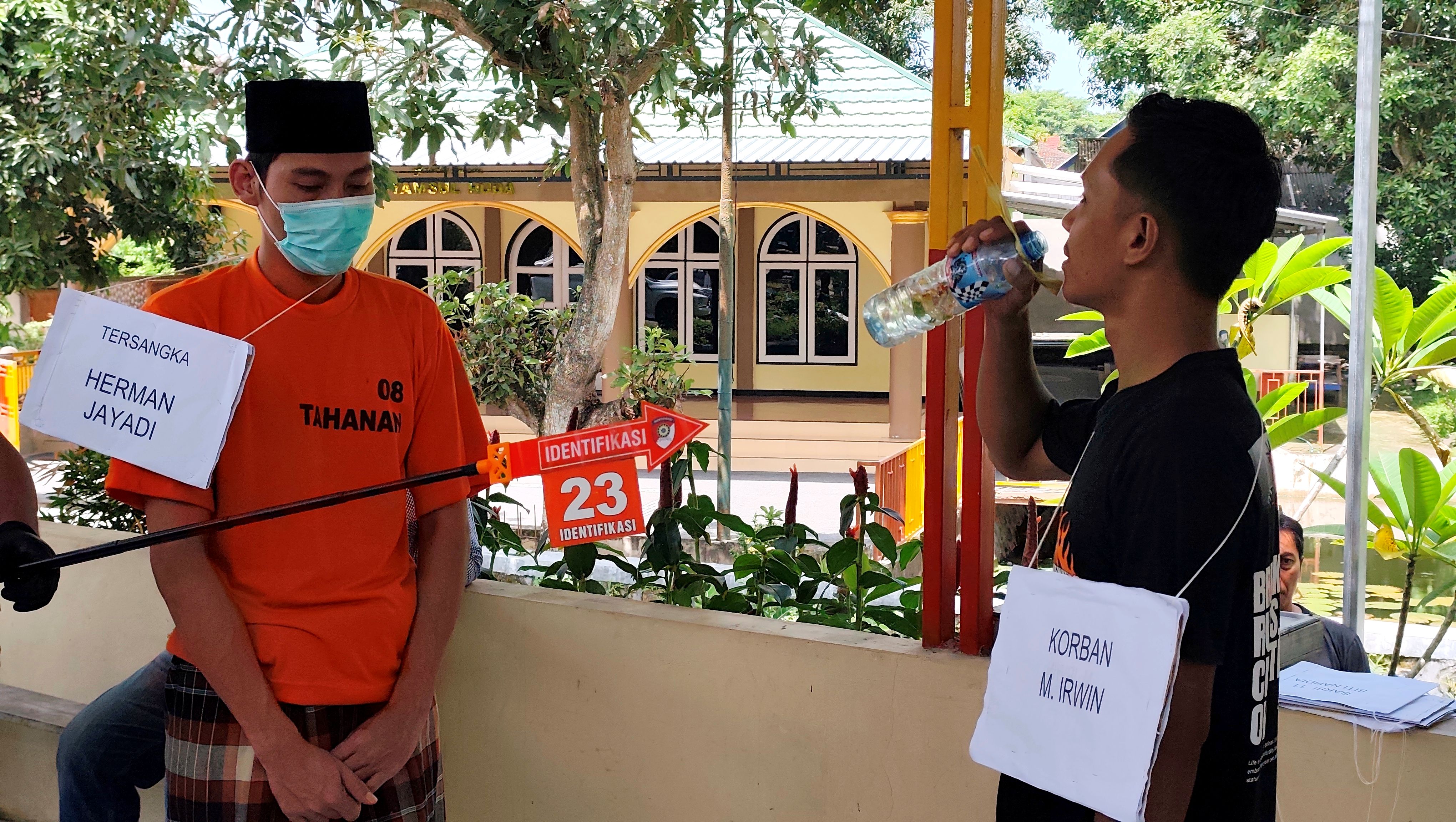 Tersangka Herman Jayadi alias Belo (kiri) memperagakan adegan 23 dimana dia memberikan minuman racun potasium kepada korban M Erwin (kanan) dalam rekonstruksi di Mapolres Loteng, Rabu (10/12).
