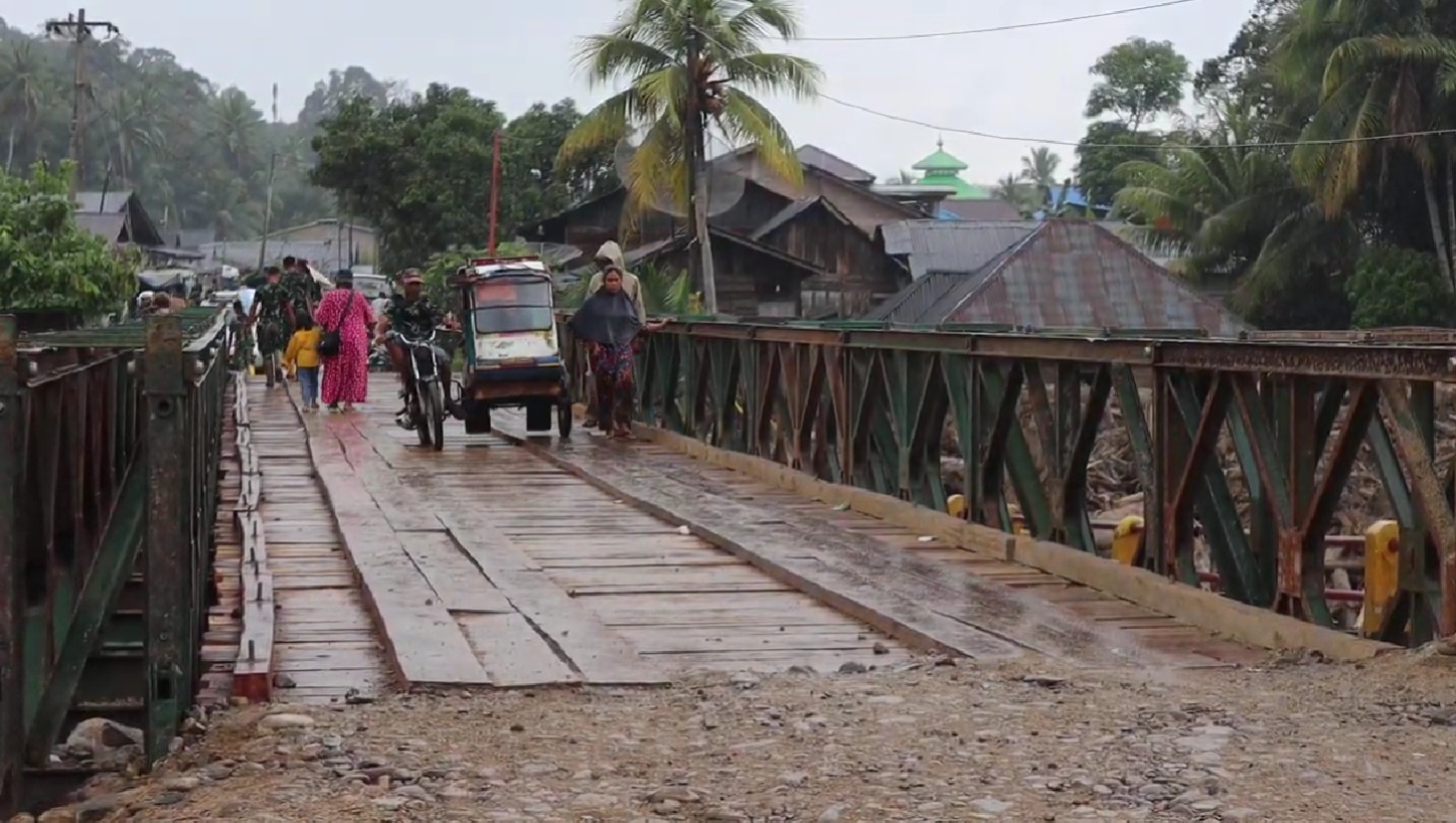 Sejumlah warga melintas di jembatan baily dari arah Provinsi Tapanuli Tengah menuju Tapanuli Selatan via Desa Garoga, Batang Toru pada Minggu (14/12).