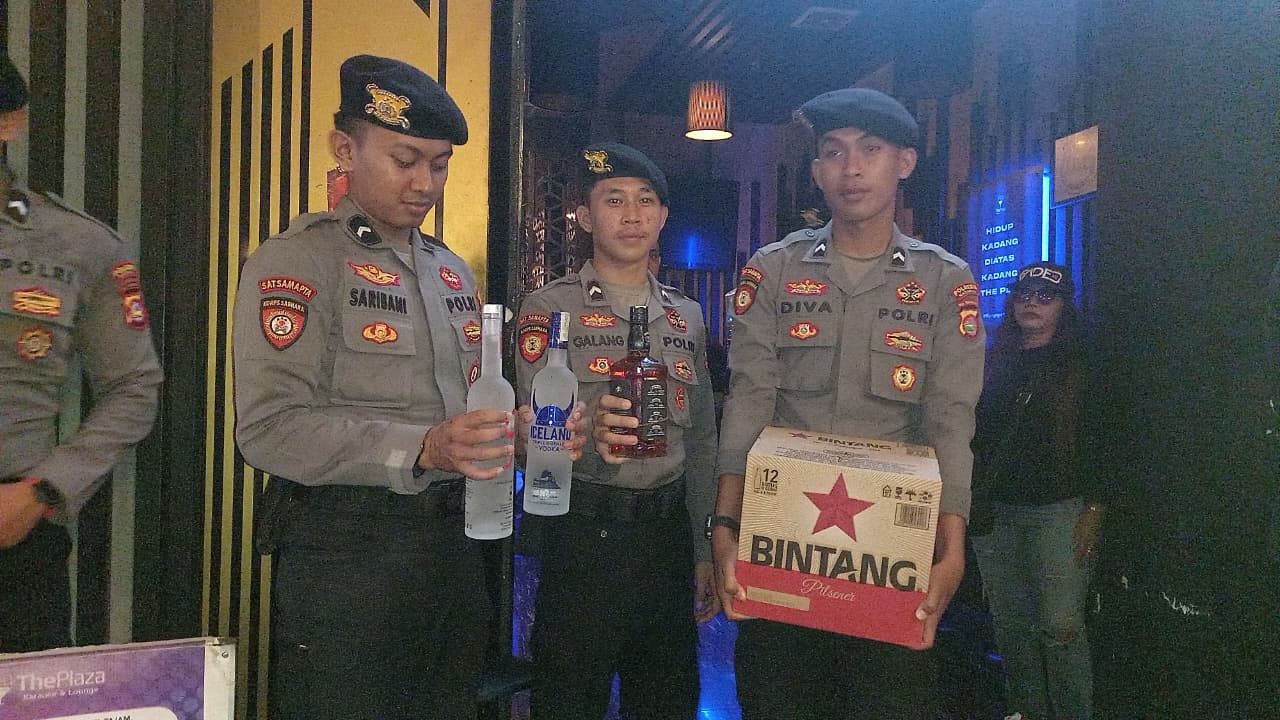 SITA BARANG BUKTI: Sejumlah anggota polisi membopong sejumlah Miras yang disita dari tempat hiburan malam, Sabtu (13/12) malam