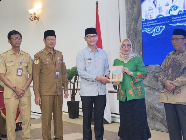 Wali Kota Mataram Mohan Roliskana menyerahkan pin emas sebagai tanda penghargaan pada perwakilan ASN purnatugas Dewi Mardiana Ariany.