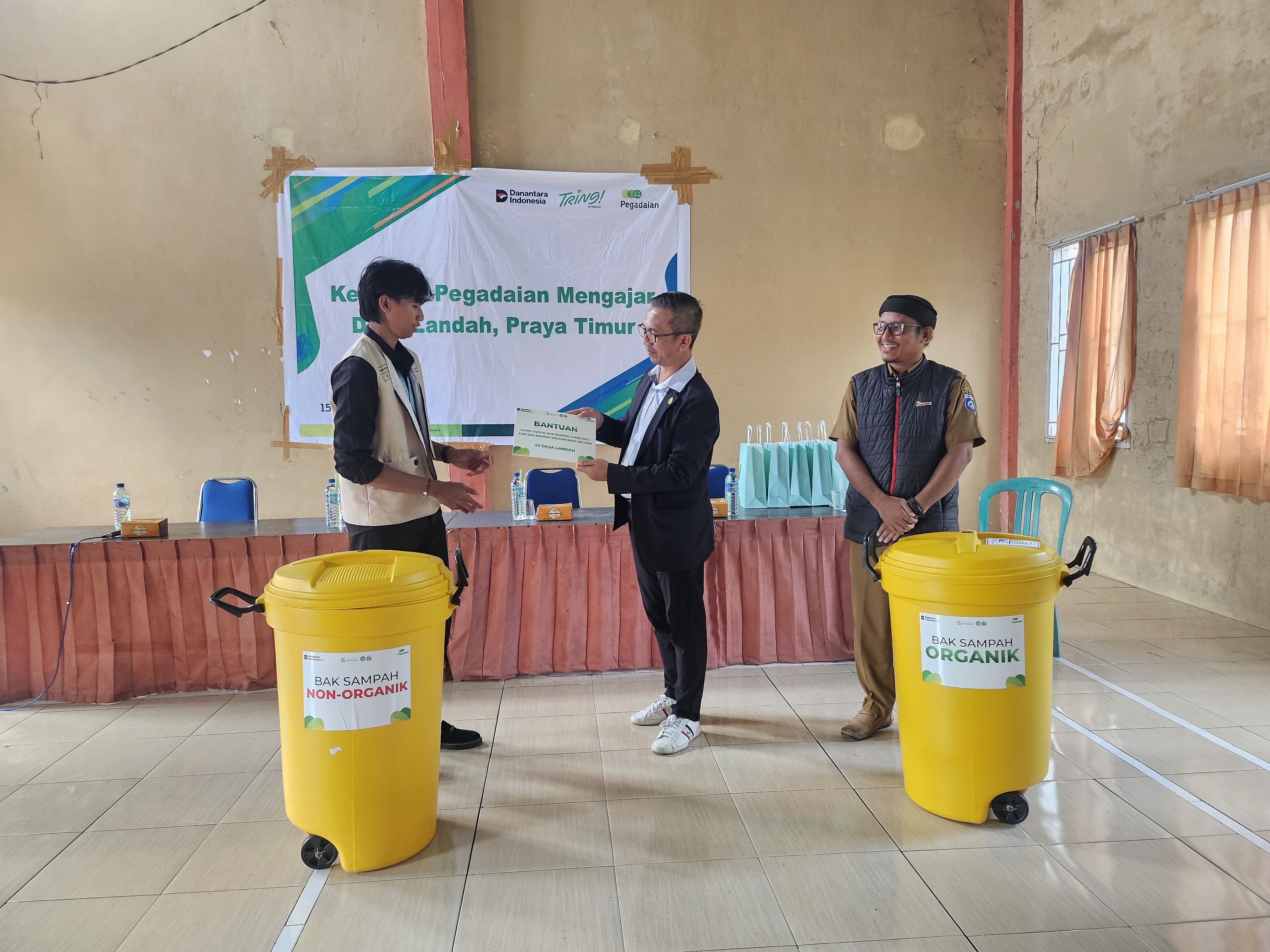 KOMITMEN NYATA: Pegadaian Cabang Praya dan Mahasiswa KKN Undikma menyerahkan bantuan sarana kebersihan dan penunjuk jalan di Desa Landah, Kecamatan Praya Timur sebagai bagian dari program bakti sosial