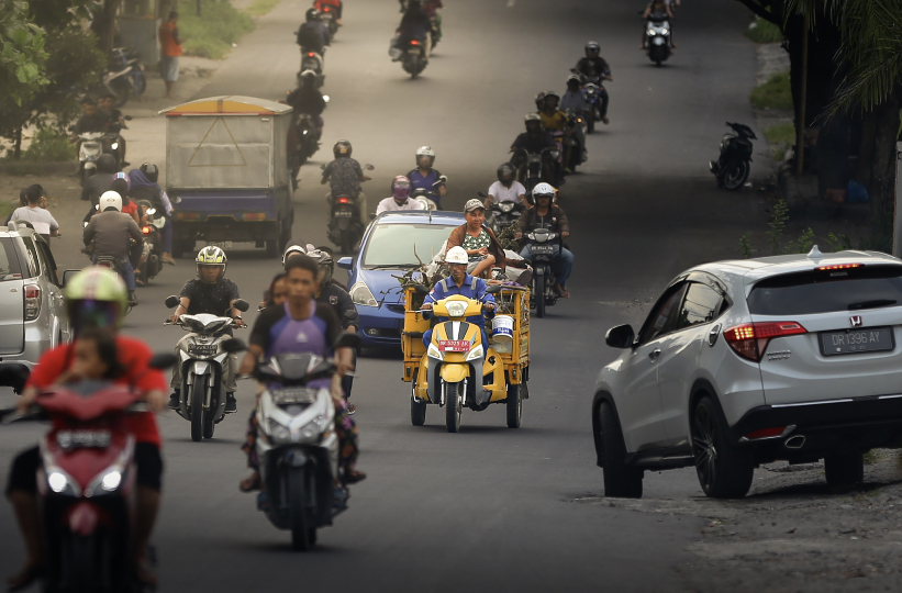 Kendaraan roda tiga pengangkut sampah melintas di jalan raya.