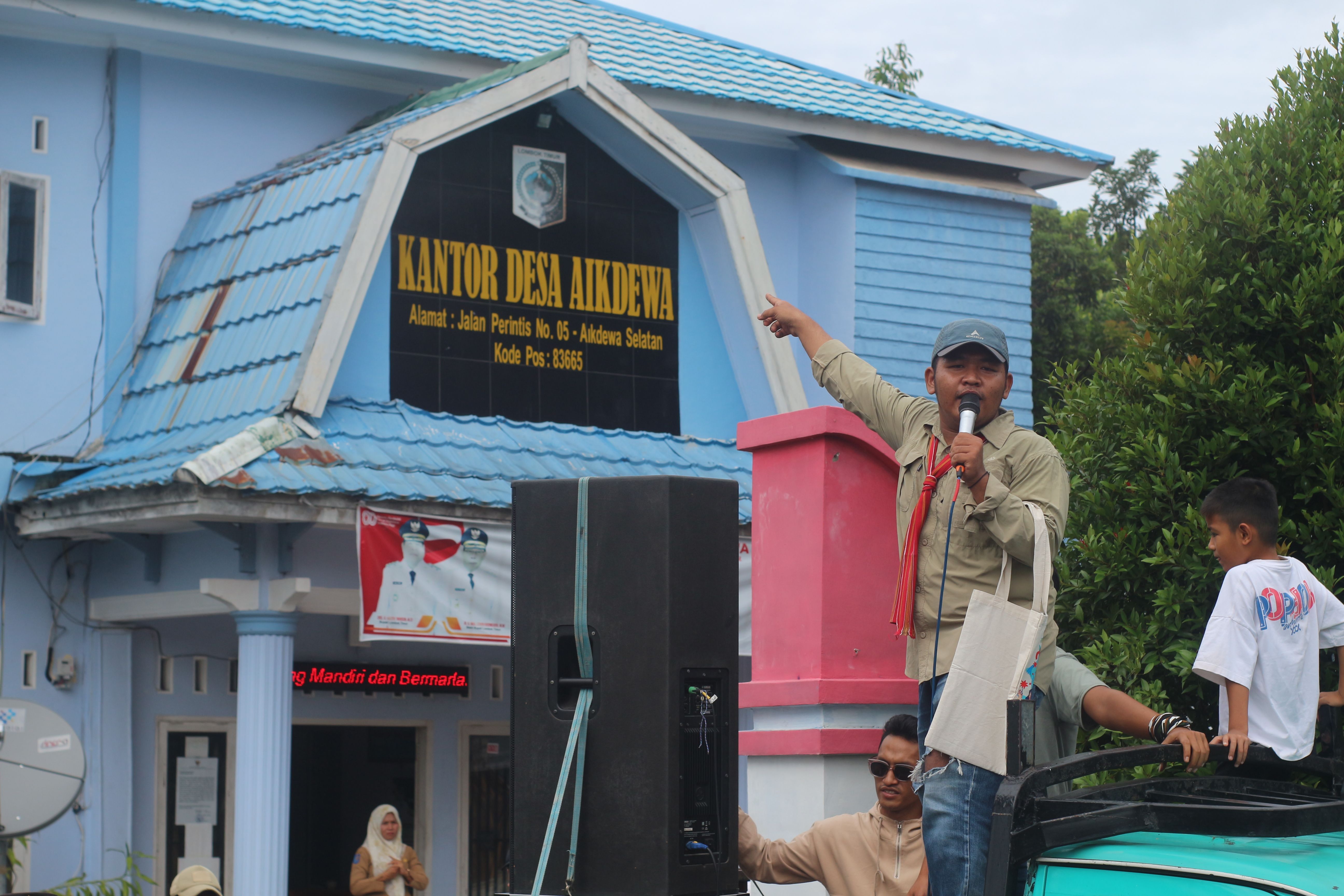 Koordinator aksi saat melakukan orasi di depan gerbang kantor Desa Aikdewa, untuk menolak pembangunan kantor Koperasi Desa Merah Putih di lapangan umum desa, Senin (22/12)