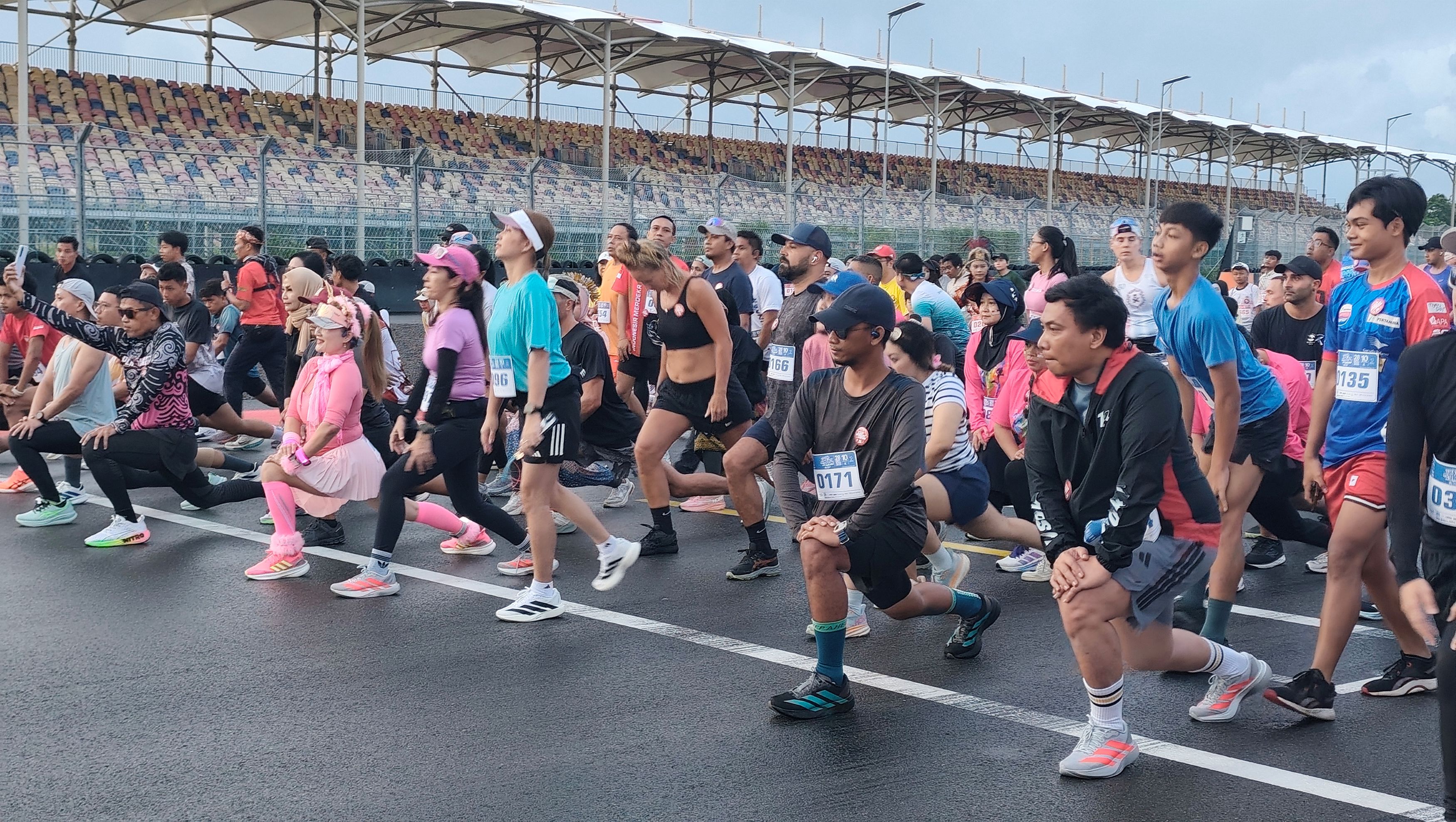 Ribuan peserta Mandalika Last Sunday Run 2025 lakukan pemanasan sebelum berlari santai mengelilingi lintasan Sirkuit Internasional Mandalika, Lombok Tengah, Minggu (28/12).