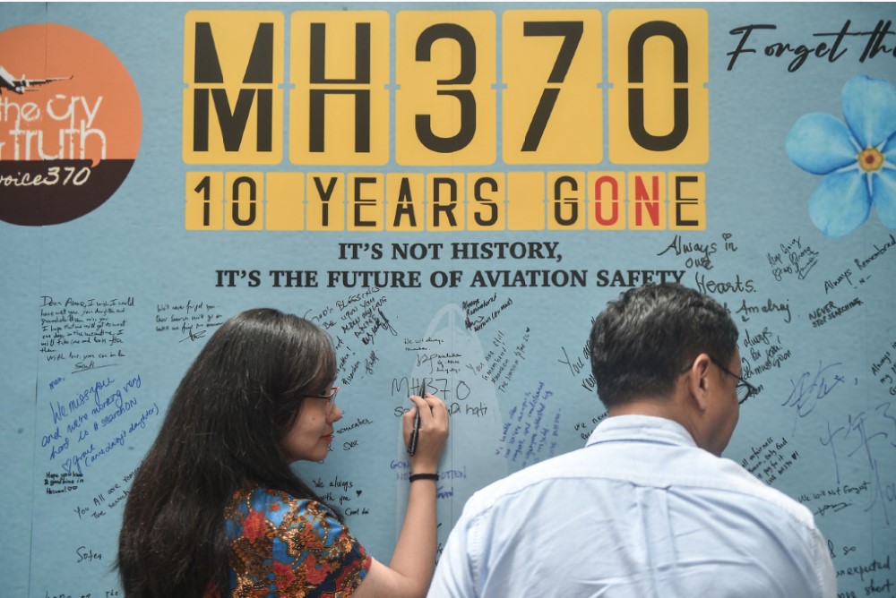 AKAN DICARI LAGI: Seorang wanita menulis pesan saat memperingati 10 tahun sejak penerbangan Malaysia Airlines MH370 yang membawa 239 orang menghilang dari layar radar pada 8 Maret 2014 lalu.