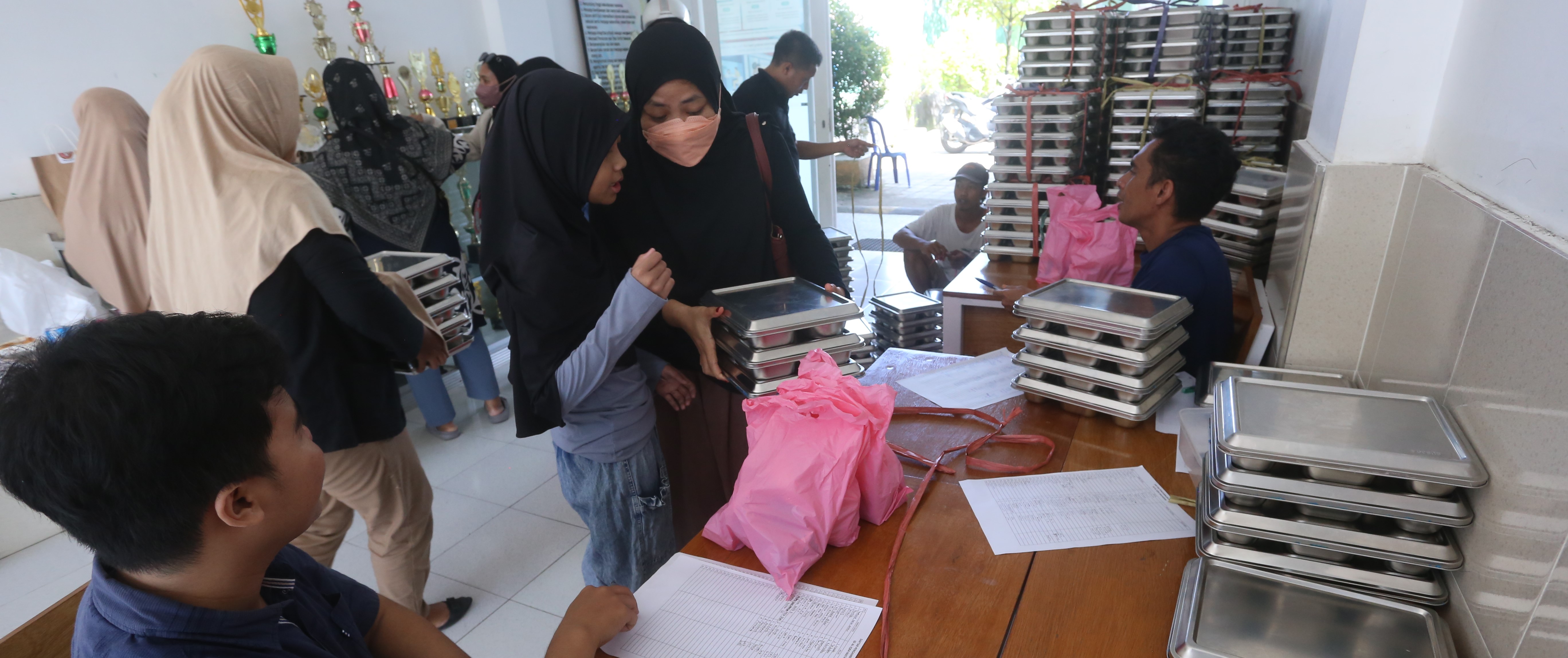 Wali murid mengambil paket MBG saat masa libur semester ganjil di SD Al Iqra Mataram, belum lama ini. Libur sekolah, MBG di Mataram tetap disalurkan fleksibel.