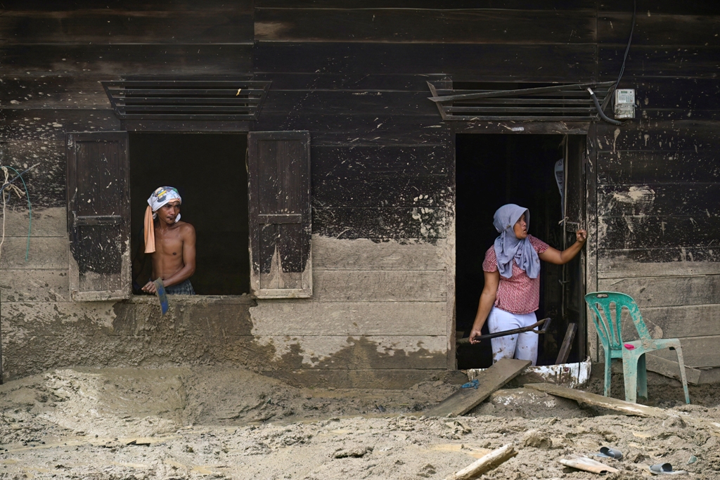 BUTUH BANTUAN: Dua warga desa membersihkan rumah mereka yang rusak akibat banjir bandang di Desa Aek Garoga, Tapanuli Selatan, Sumatera Utara, pada Sabtu (27/12).