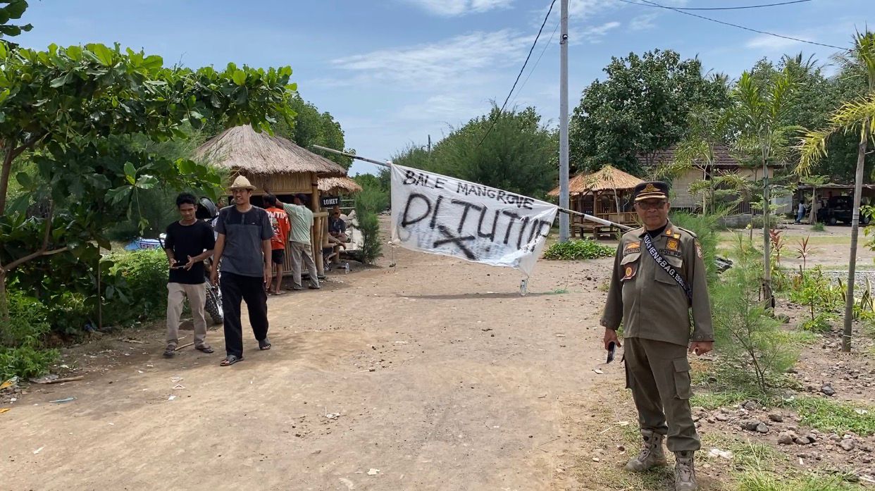 seorang petugas dari Satpol-PP Lotim saat berjaga di depan pintu masuk ekowisata Bale Mangrove yang ditutup warga saat aksi unjuk rasa.