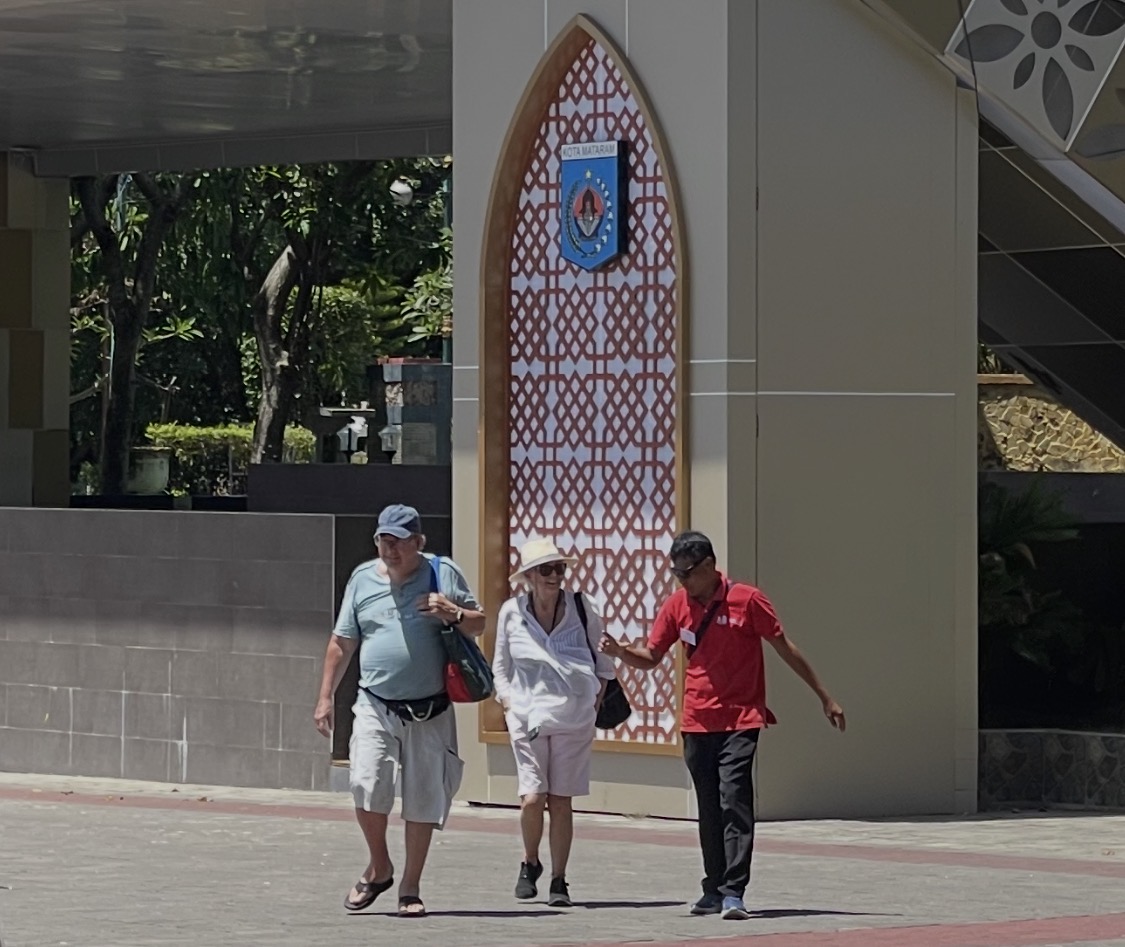 Seorang pemandu wisata tengah mengajak dua orang wisatawan mancanegara berkeliling di taman Sangkareang Kota Mataram.