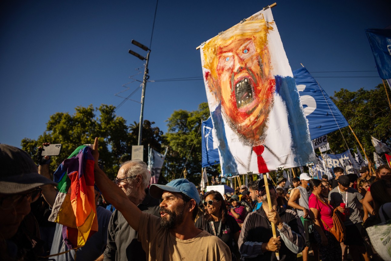 PROTES TRUMP: Seorang pria memegang lukisan yang menggambarkan Presiden Amerika Serikat Donald Trump saat demo menentang intervensi AS di Venezuela, di Buenos Aires, Senin (5/1).