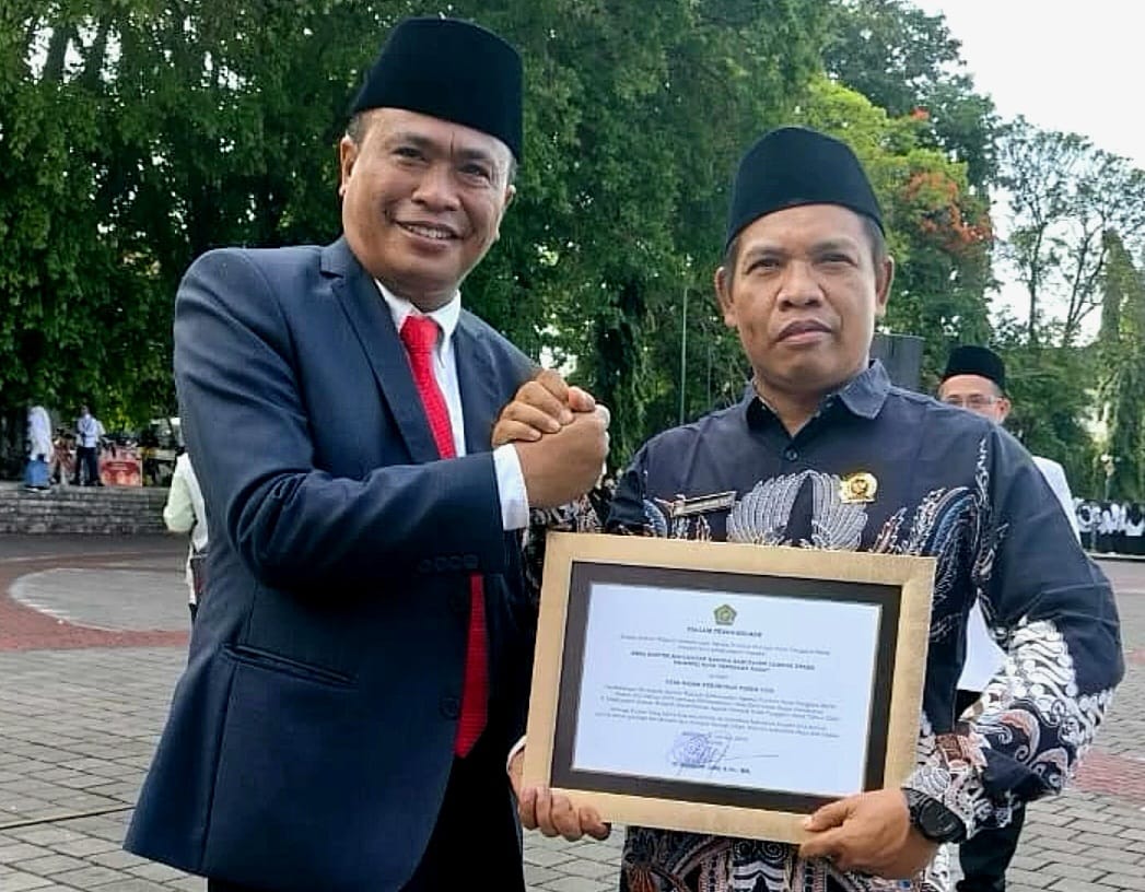MEMBANGGAKAN: Kepala Desa Bentek Warna Wijaya (kanan) menerima penghargaan Desa Sadar Kerukunan, yang diberikan Kepala Kanwil Kemenag NTB