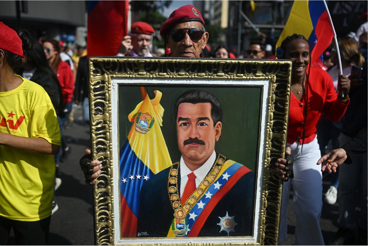 TUNTUT PEMBEBASAN: Seorang pria memegang foto mantan Presiden Venezuela Nicolas Maduro saat unjuk rasa mendukung Maduro dan istrinya, Cilia Flores, di Caracas Selasa (6/1). Tiongkok mendesak bebaskan.