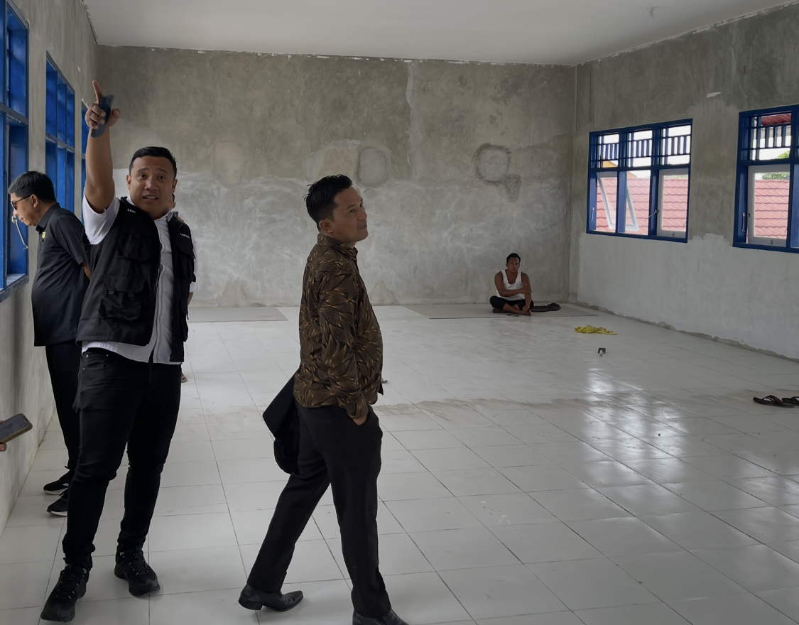Ahmad Azhari Gufron menunjuk detail tembok yang belum selesai dicat tapi telah dinyatakan pekerjaan 100 persen.