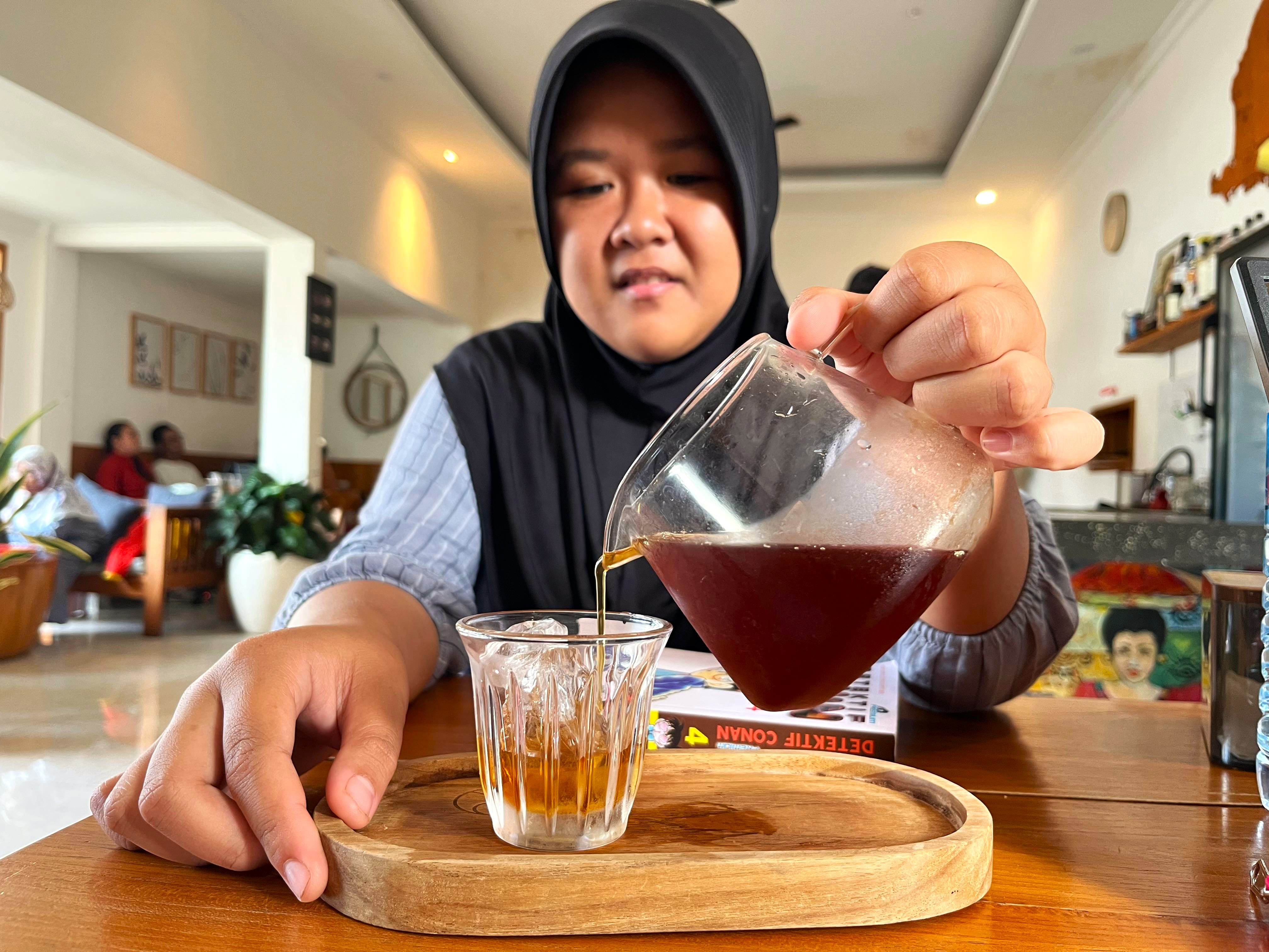 SENSASI UNIK: Salah satu pengunjung Ratih Coffee & Eatery yang tengah menikmati Japanese Iced Coffee, baru-baru ini.
