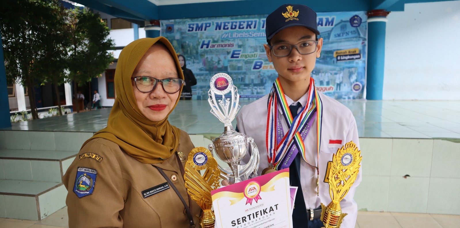 Siswa SMPN 15 Mataram Dimas Rizky Andrean bersama kepala sekolah menunjukkan medali dan piala yang diraihnya pada lomba olimpiade sains. Koleksi 42 medali sains, Dimas bidik emas OSN nasional.