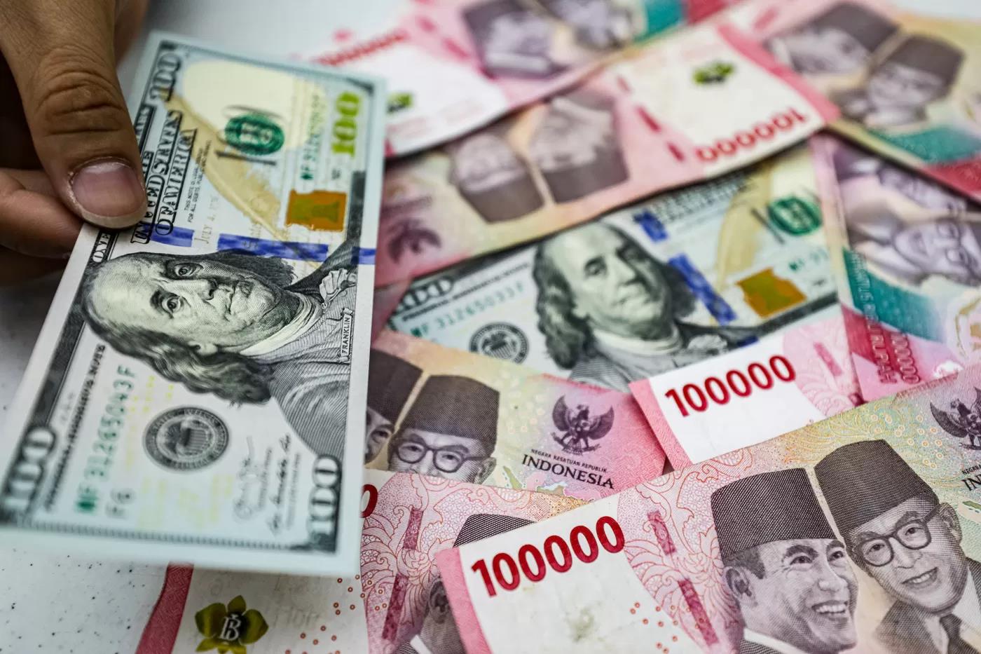 Pegawai menunjukan mata uang Dolar Amerika dan Rupiah di salah satu kantor cabang Bank Mandiri di Jakarta, Selasa (22/7/2025). (Salman Toyibi/Jawa Pos)
