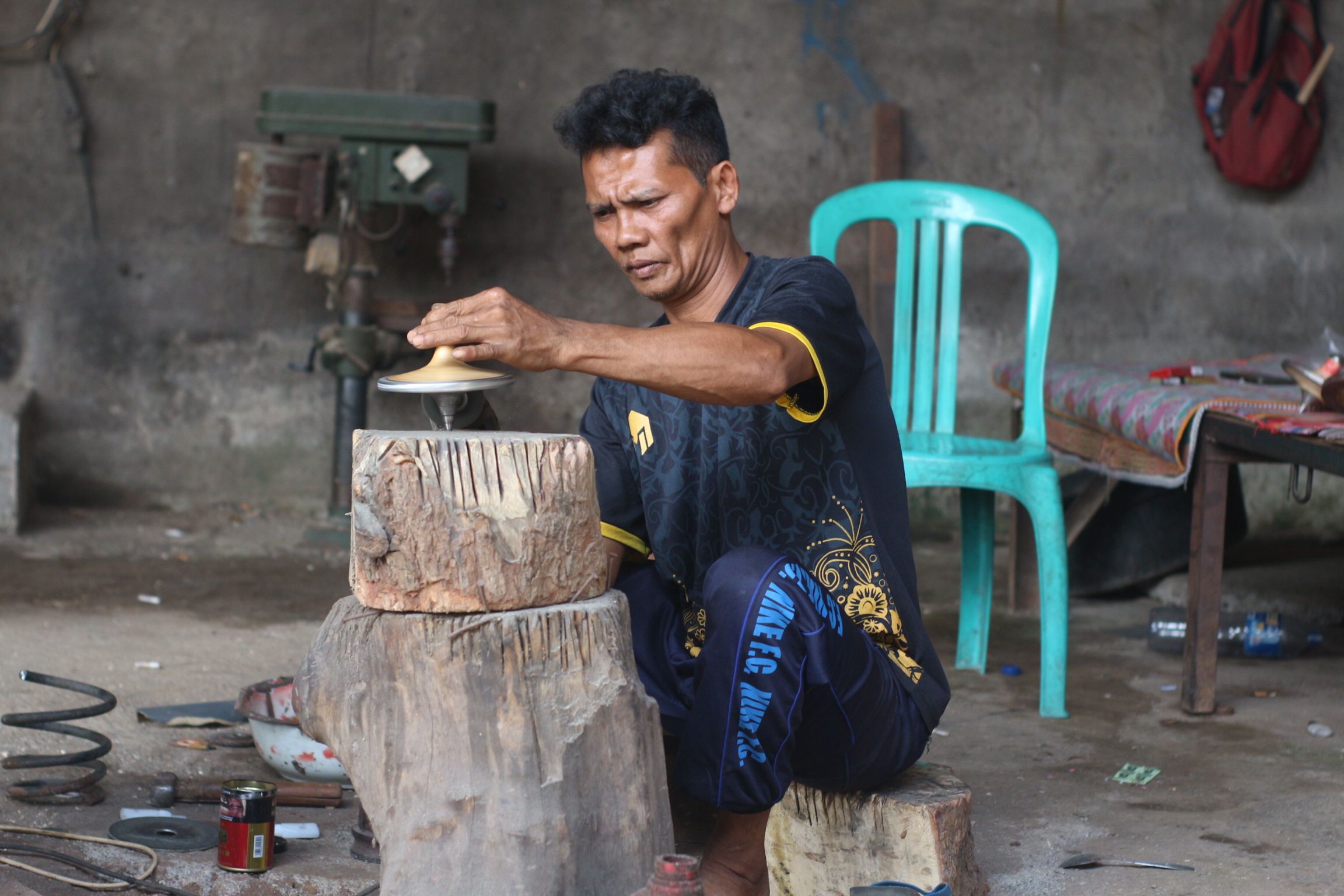 Mahsun salah seorang perajin permainan tradisional gasing menghaluskan gasing yang sudah dibuat di pande besi miliknya