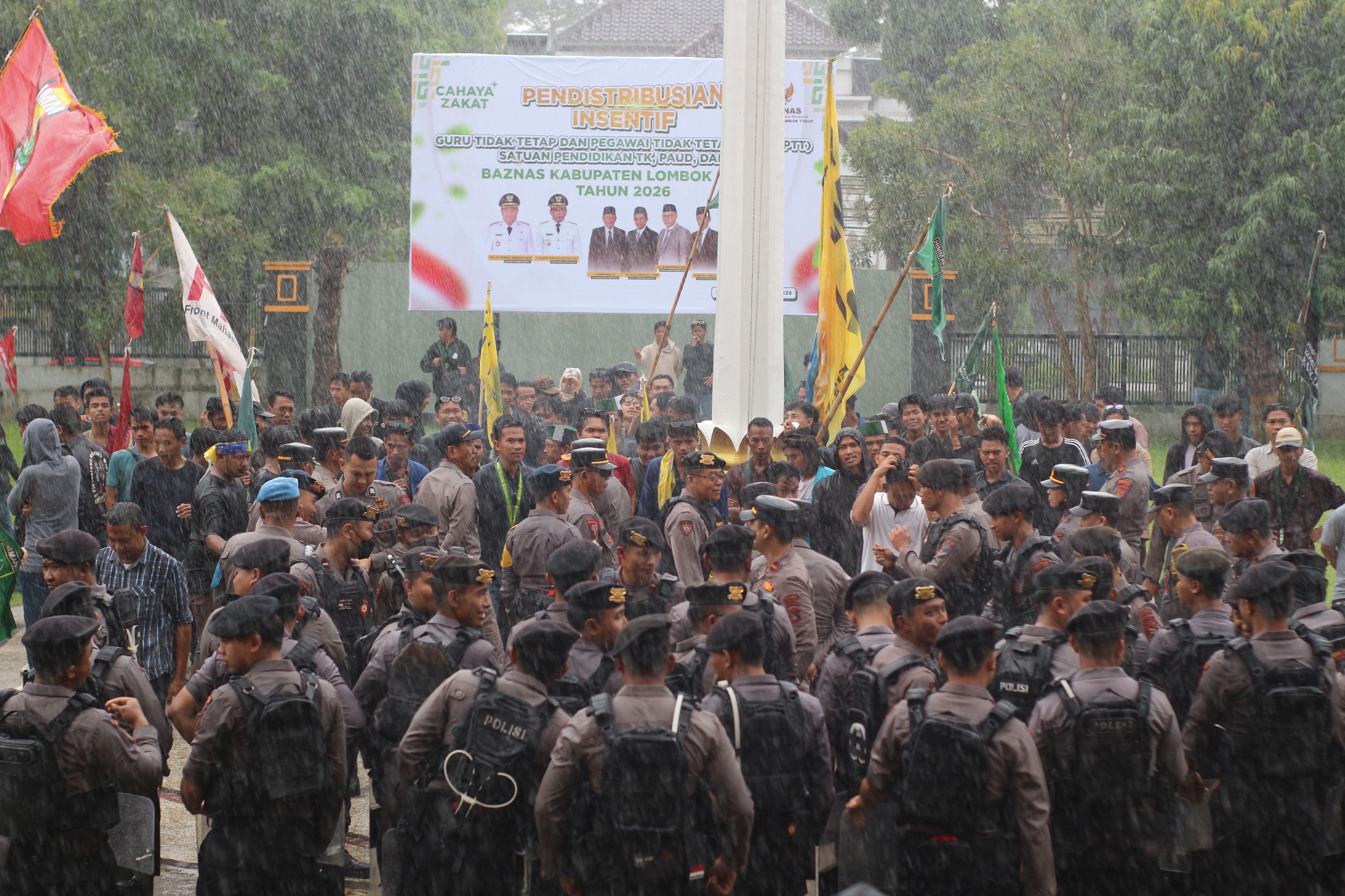 DIGUYUR HUJAN: Puluhan Mahasiswa memilih bertahan di tengah hujan lebat untuk melakukan aksi demonstrasi di halaman kantor Bupati Lotim, untuk mendesak supaya Kadispar dan Stafsus Bupati dicopot