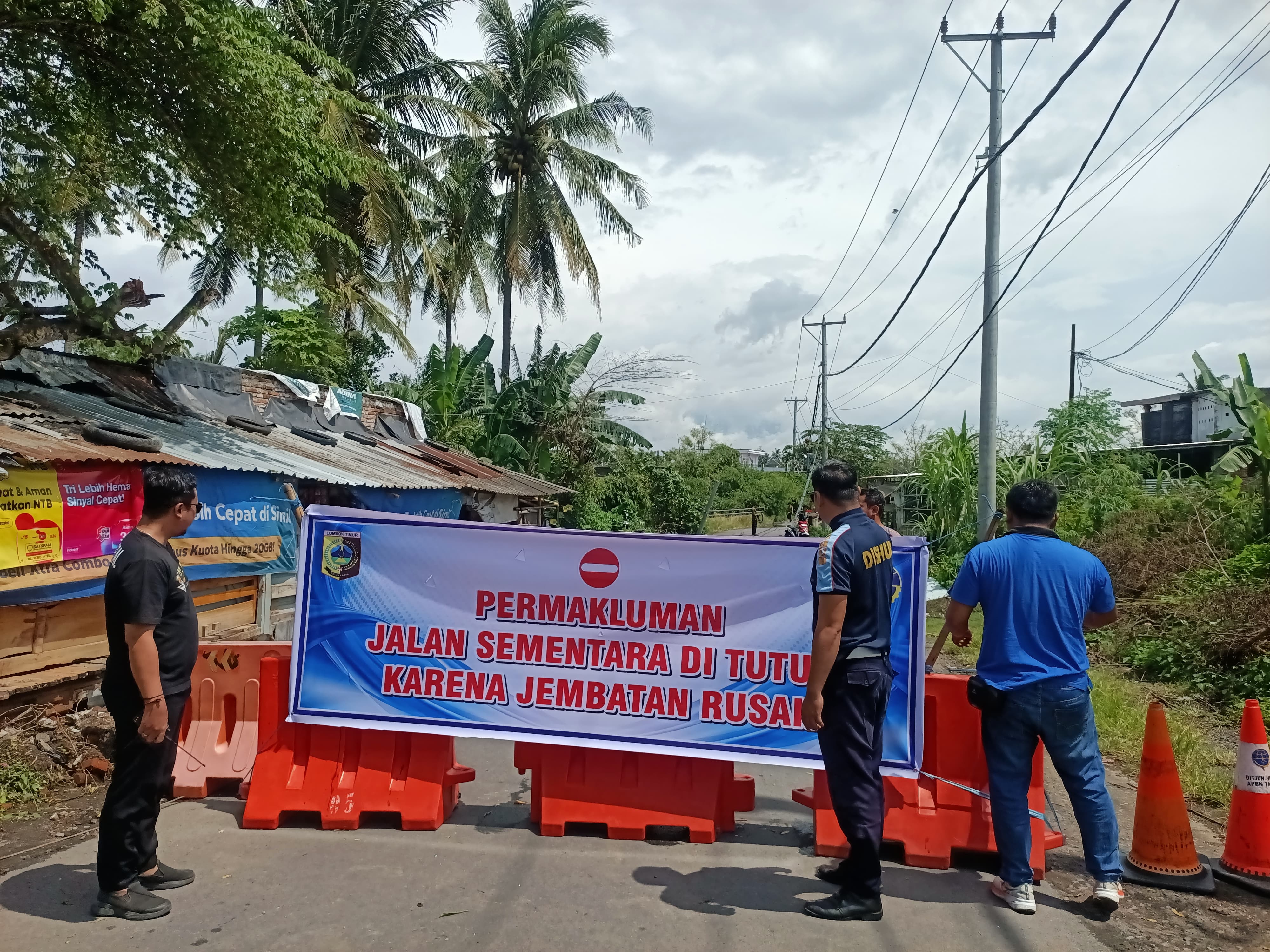 NYARIS PUTUS: Petugas kepolisian sedang menutup jalan penghubung antara Kelurahan Pancor dengan Sekarteja yang nyaris putus akibat hujan lebat