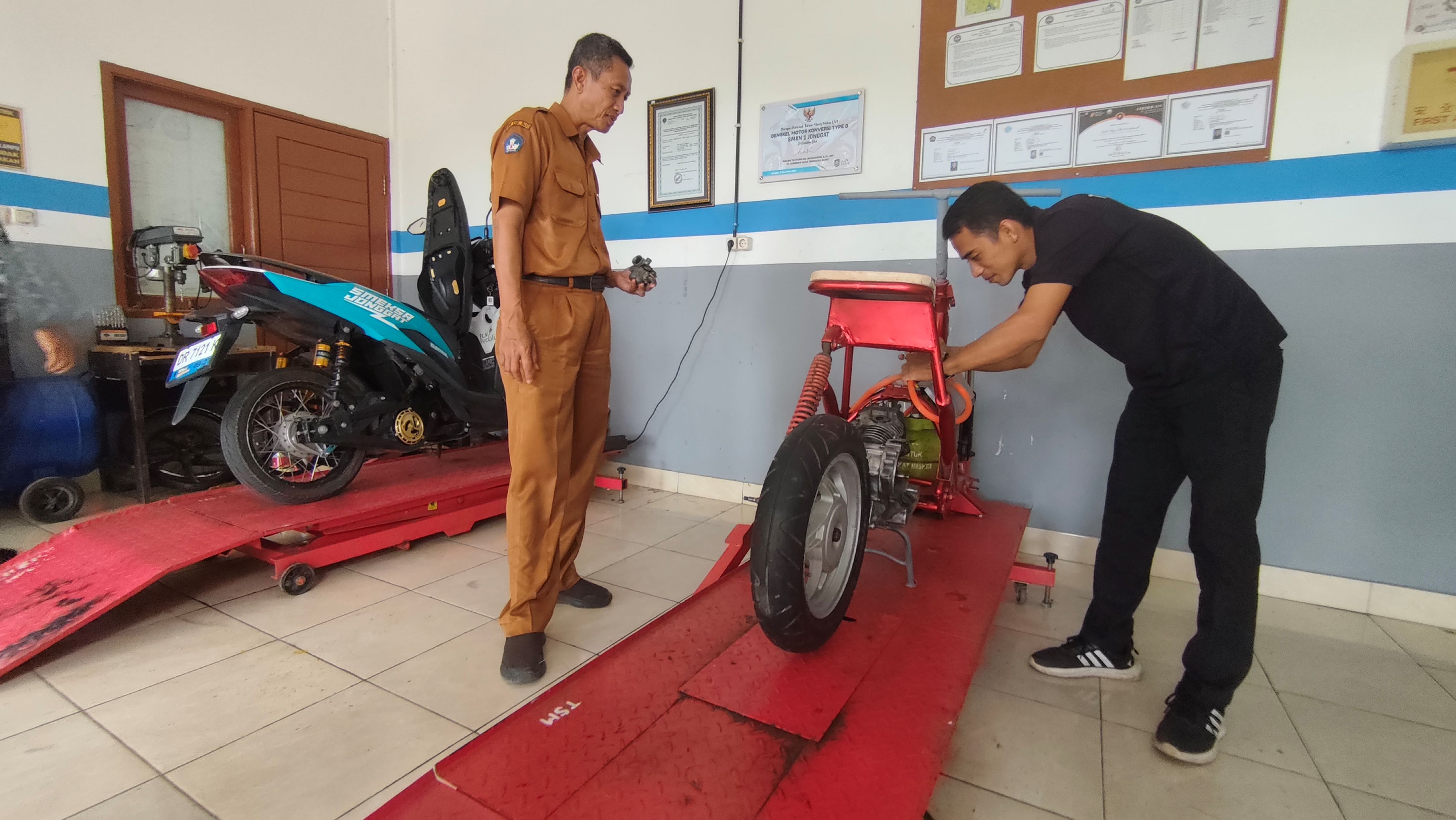 Kepala SMKN 1 Jonggat Ruju Rahmad (kiri) menunjukkan inovasi baru kendaraan energi terbarukan dengan mengembangkan Motor Berbasis Gas, di Desa Jonggat, Kecamatan Jonggat, Lombok Tengah.