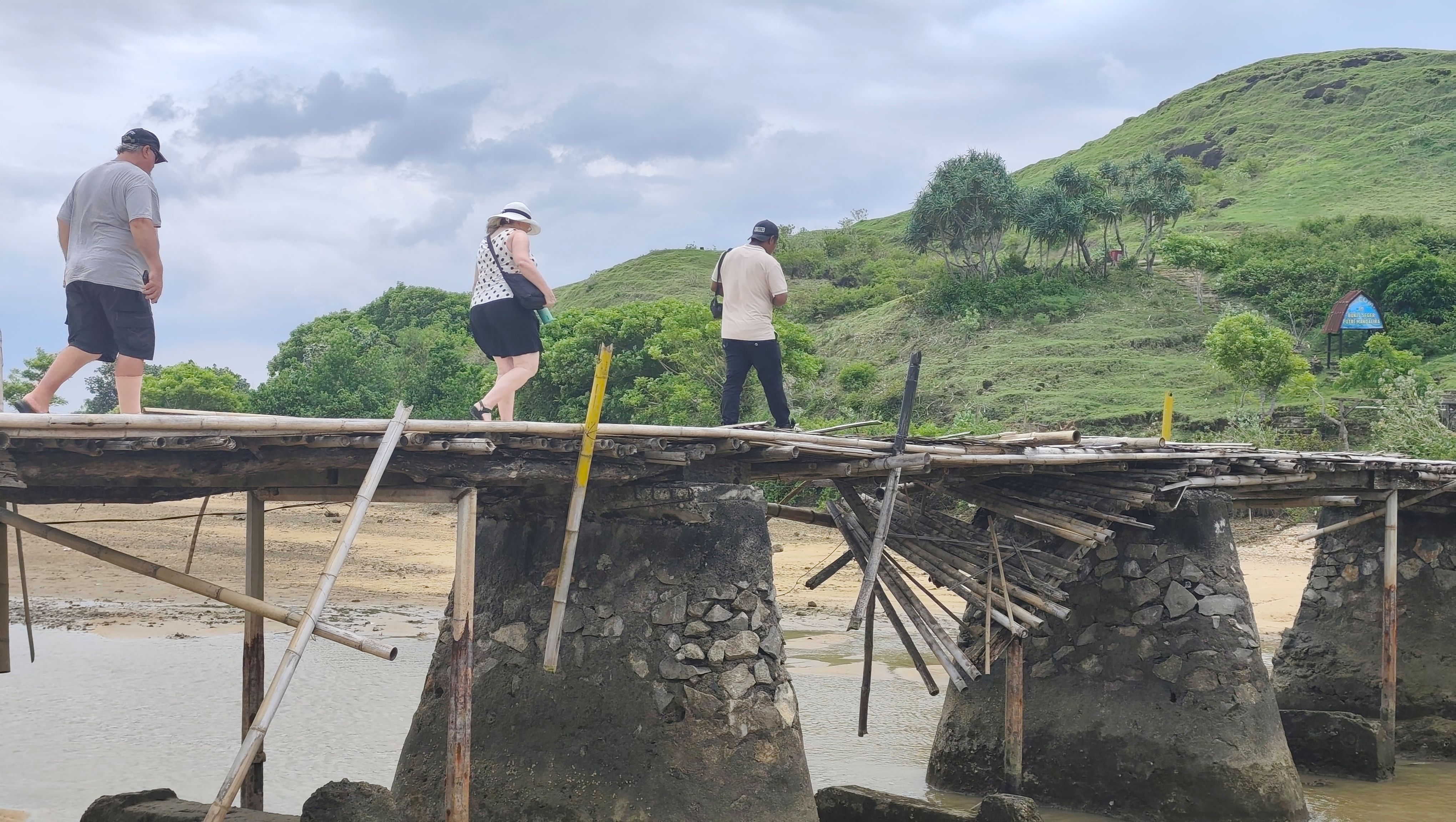 Sejumlah wisatawan asing saat melintasi jembatan semi permanen menuju perbukitan Seger yang akan menjadi pusat lokasi event budaya Bau Nyale di Lombok Tengah.