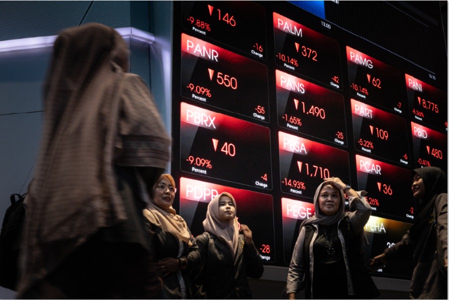 SEMPAT ANJLOK: Sejumlah pengunjung berfoto di depan papan elektronik yang  menampilkan harga saham di BEI di Jakarta pada Kamis (29/1).