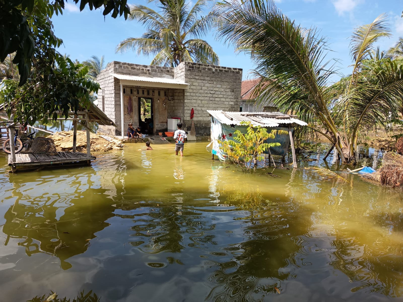 TERENDAM BANJIR: Seorang anak sedang mandi di depan rumahnya yang terendam banjir.