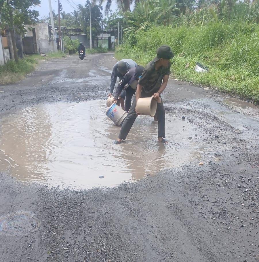 Warga Desa Kalijaga Timur saat menguras air di di tengah jalan Kalijaga Timur yang rusak