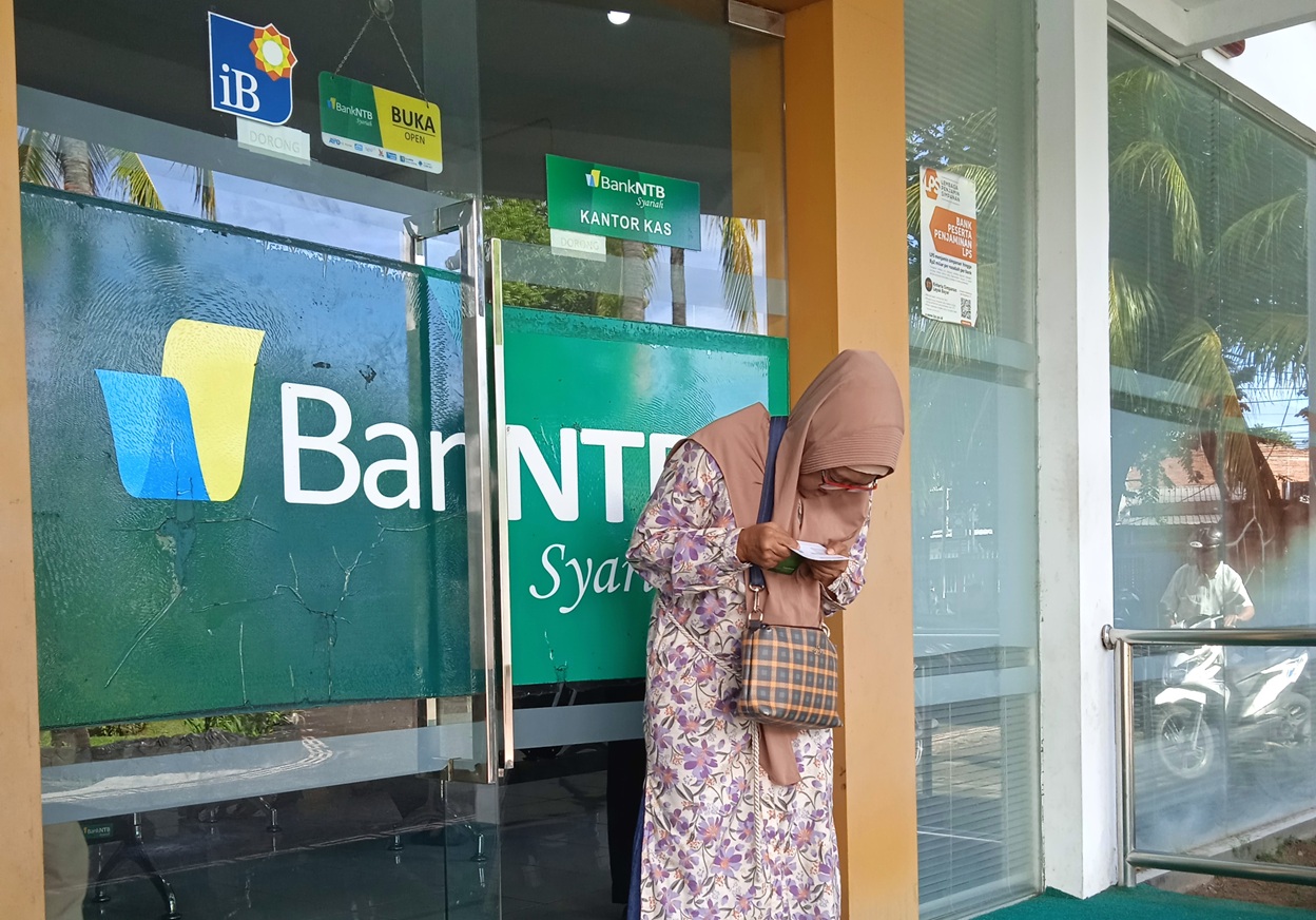 BANK DAERAH: Seorang nasabah salah satu bank di Mataram memeriksa buku rekening sesaat usai transaksi, beberapa waktu lalu.