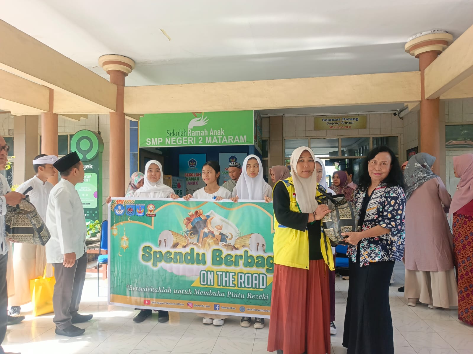 Plt Kepala SMPN 2 Mataram Dra. Ni Nengah Sri Swathi menyerahkan paket sembako kepada warga.