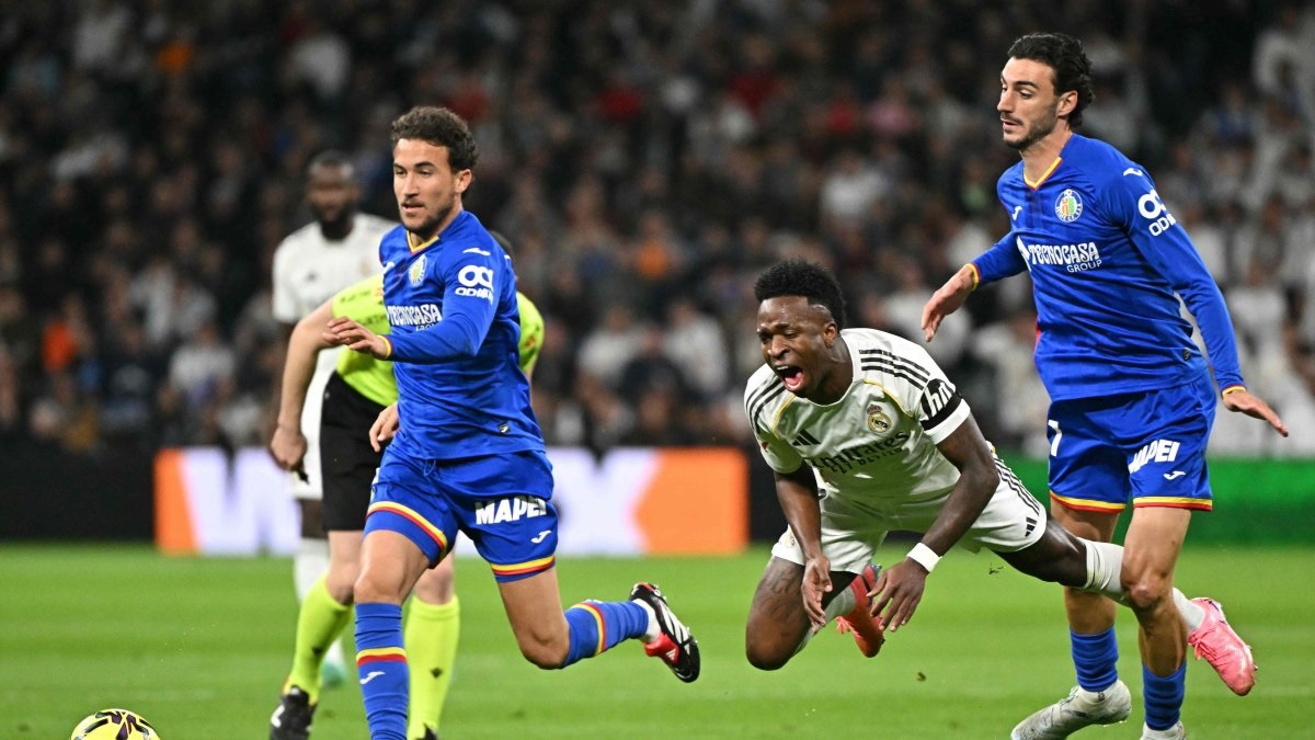 Bek Getafe CF Juan Iglesias (kanan), berebut bola dengan penyerang Real Madrid Vin&iacute;cius J&uacute;nior (tengah) dalam pertandingan Liga Spanyol di Santiago Bernab&eacute;u,  2 Maret 2026. (AFP)