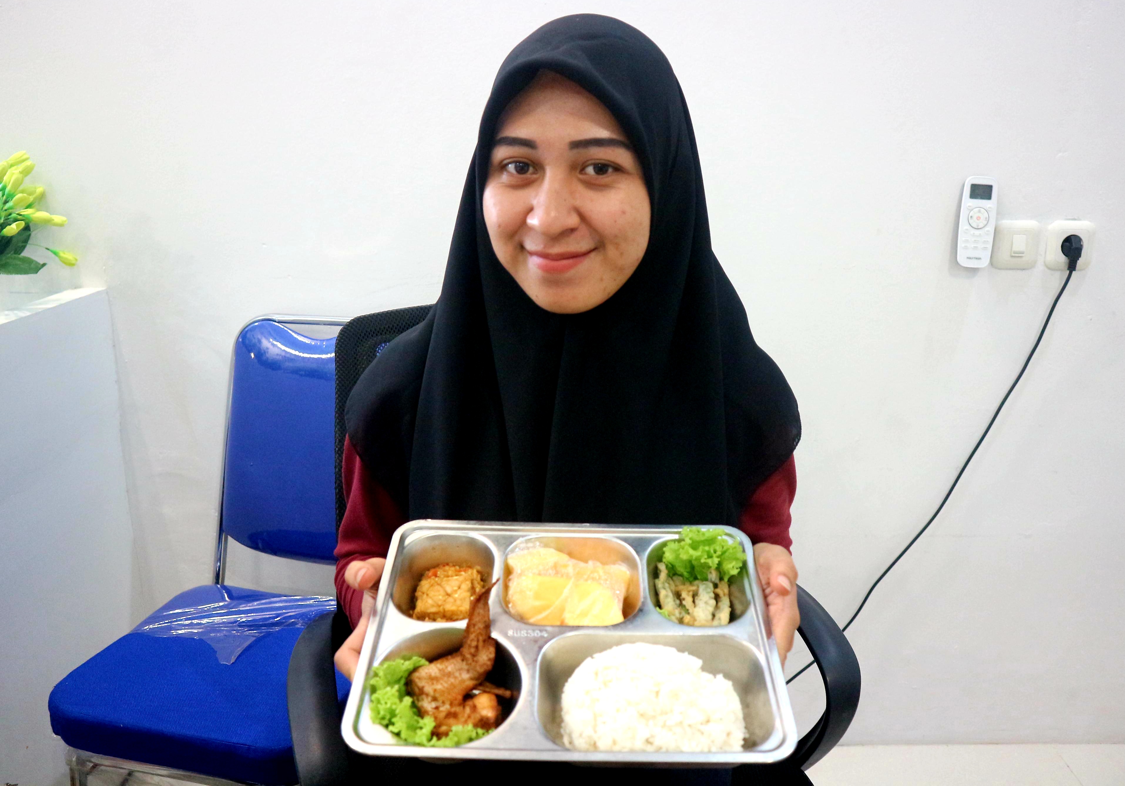 HASILKAN MENU BERKULITAS: Ahli Gizi SPPG Dasan Tapen Dina Aulia menunjukkan salah satu menu MBG yang dihadirkan bagi siswa Ponpes penerima manfaat untuk berbuka puasa.  