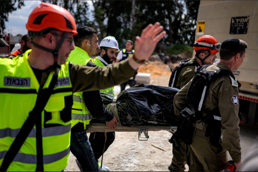 Pasukan pertahanan sipil membawa jenazah korban yang tewas akibat dampak proyektil Iran di Yehud, Israel tengah, Senin (9/3). 