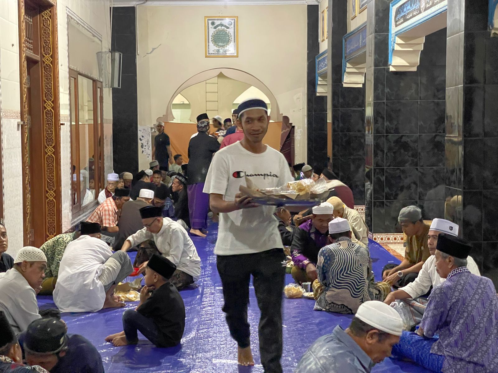 Remaja masjid mengantarkan gibungan ke jamaah yang hadir, satu gibungan untuk tiga orang. 